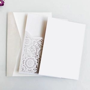 Detail of white laser-cut wedding invitation set with floral hollow pattern and envelope