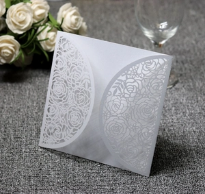 Detailed laser-cut floral pattern on white wedding invitation card with elegant roses
