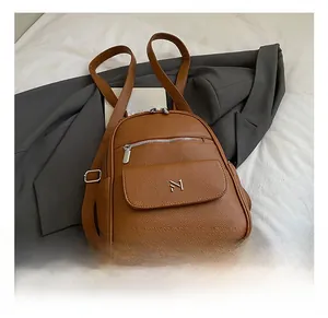 Detail of brown litchi pattern PU backpack featuring silver hardware and a front magnetic pocket