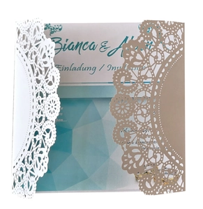 Detail of laser-cut lace wedding invitation with floral patterns on kraft and white paper