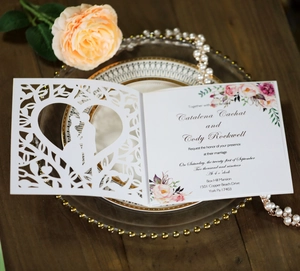 Detailed laser-cut wedding invitation featuring heart silhouettes on elegant table setting
