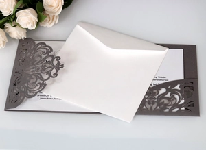 Macro detail of laser-cut wedding invitation featuring intricate grey filigree and cream card