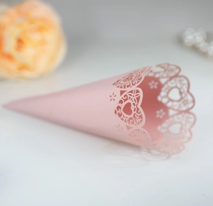 Close-up of pink laser-cut lace cone with heart and floral patterns for wedding petals
