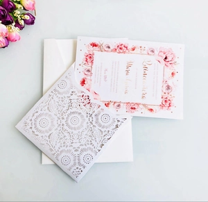 Macro shot of laser-cut burgundy invitation with floral inner card and white envelope