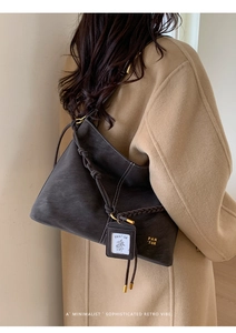 Detail of vintage dark brown leather bucket bag with braided strap and gold brand logo