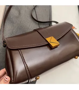 Detail of dark brown crossbody bag with gold envelope clasp and premium faux leather texture