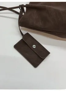 Detail showing deep brown faux leather texture and a detachable mini card pouch with silver clasp