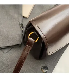 Close-up of premium dark brown leather handbag with luxury gold circular metal hardware