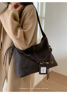 Detail of vintage dark brown suede tote with decorative braided ropes and metal hardware