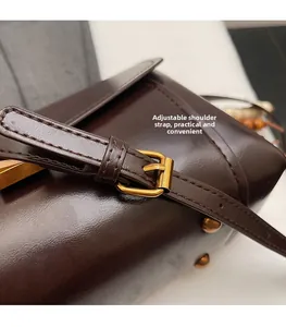 Close-up of brown faux leather strap with adjustable gold-tone buckle and stitching