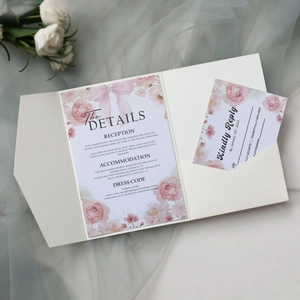 Close-up of elegant floral wedding invitation cards with pink bows on blue tulle
