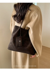 Close-up of minimalist dark brown suede tote bag with matching card holder on model