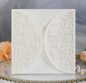 Macro detail of laser cut floral pattern on ivory white wedding invitation card