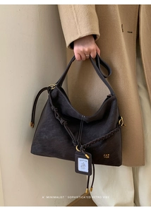 Detail of dark brown leather bucket bag with braided rope and tassel accents