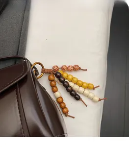 Detail of ethnic multi-color wooden bead pendant charm on dark brown leather crossbody bag