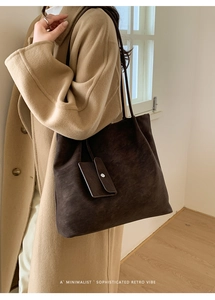 Deep brown matte tote bag with small pouch worn by a model in a minimalist room