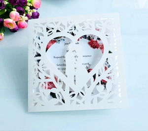 Detail of laser-cut heart pattern on white wedding invitation with floral insert