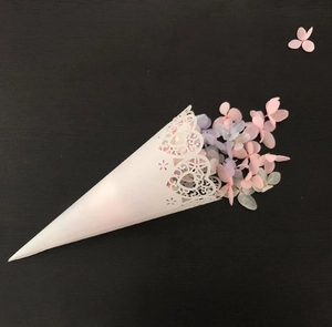Detail of white laser-cut lace cone filled with colorful dried flower petals for wedding