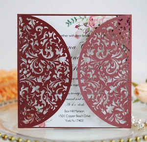 Detail of laser-cut burgundy wedding invitation with elegant floral patterns and inserts