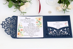Close-up of laser-cut lace invitation in navy blue with white floral inner cards