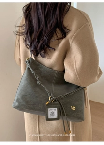 Detail of vintage dark green leather tote with braided straps and card holder accessory