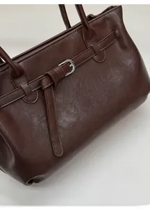 Detail of dark brown tote bag featuring elegant silver metal buckle and strap craft