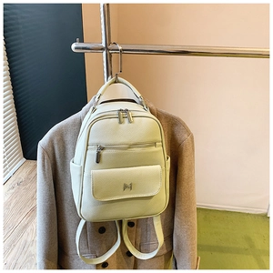 Detail view of light green leather backpack with lychee grain texture and metal logo