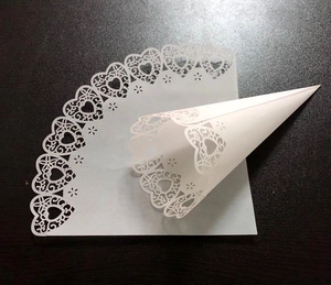 Detailed laser-cut white heart and flower lace patterns on paper wedding flower cones