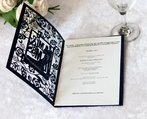 Detail of laser-cut navy wedding invitation with intricate floral lace and gold accents