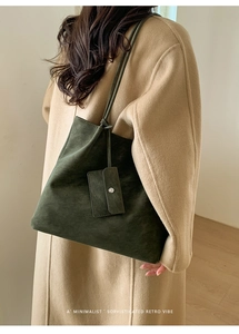 Detail of dark green retro tote bag with minimalist small hanging pouch on a coat