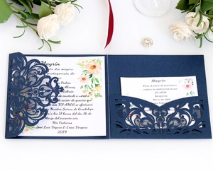 Close-up of laser-cut navy blue glitter invitation with floral inner card and silk ribbon