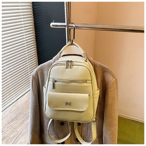 Detail of light lime green backpack featuring lychee texture leather and M metal logo