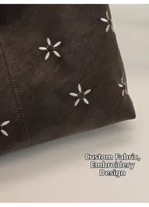 Détail du tissu personnalisé et broderies de fleurs blanches sur le sac fourre-tout