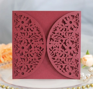 Intricate laser-cut leaf and floral patterns on elegant burgundy square wedding invitations