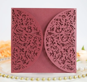Detail of laser-cut burgundy invitation cover with elegant floral patterns on pearlescent paper