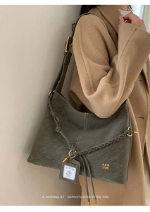 Close-up of a grey textured leather tote bag with woven shoulder strap detail