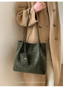 Deep green suede tote bag detail with long strap and matching small pouch on camel coat
