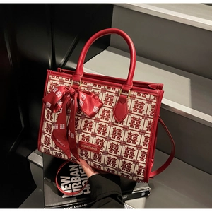 Detailed shot of red bridal tote bag with XI patterns and a large decorative silk bow