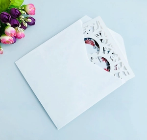 Detail of laser-cut ivory wedding invitation with elegant hollow patterns and floral insert