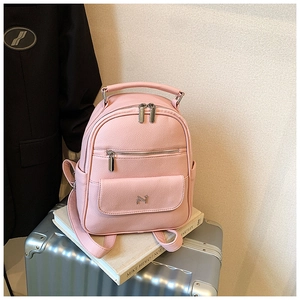 Detailed macro view of pink lychee grain leather backpack with metal M logo on a suitcase