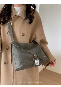 Detail of dark grey vintage bucket bag with woven shoulder strap and gold brand logo