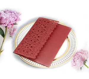 Elegant burgundy laser-cut lace wedding invitation card on decorative plate