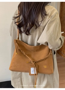 Detail of camel brown tote bag featuring a woven strap and a hanging card holder accessory