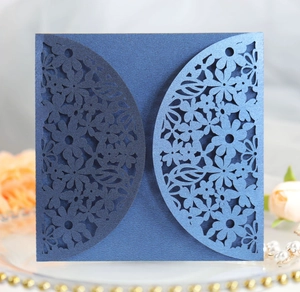 Macro detail of laser-cut floral pattern on navy blue pearlescent paper wedding invitation