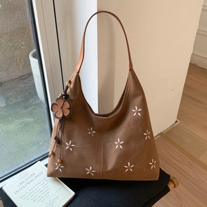 Détail d'un sac cabas en daim marron avec broderie florale et breloque en perles