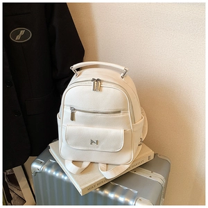 Close-up of beige litchi grain backpack with silver metal logo and premium leather texture