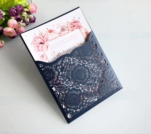 Detail of laser-cut navy blue wedding invitation with white floral insert and pink roses