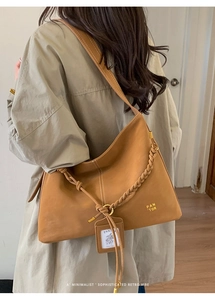 Detail of caramel vintage leather bucket bag featuring woven handle and knot accents