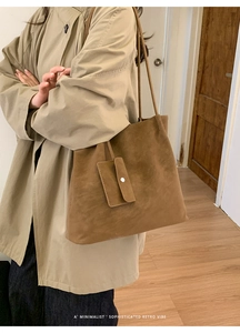 Detailed side view of a brown suede tote bag with matching pouch on a minimalist model