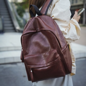 Sac à dos en cuir marron foncé avec poche zippée avant dans un décor de place urbaine